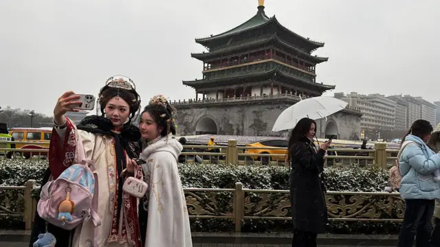 Дві жінки в традиційних костюмах роблять селфі перед дзвіницею Сіаня 31 грудня 2025 року в Сіані, провінція Шеньсі, Китай