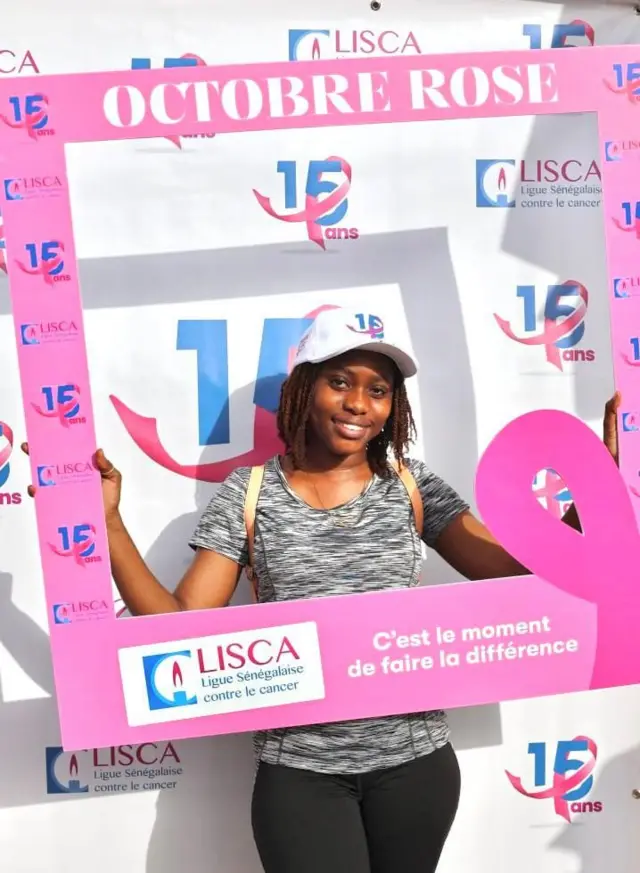 Une jeune dame posant avec des images de sensibilisation à Dakar le 29 septembre 2024