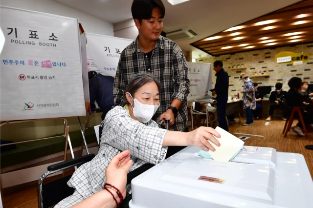 경북 포항시 북구 죽도동 포항고용복지플러스센터에 마련된 투표소에서 휠체어를 탄 유권자가 선거사무원의 도움을 받아 소중한 한표를 행사하고 있다.