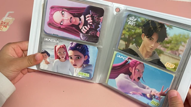 一名孩子的双手正拿着一本收纳了《K-pop猎魔女团》角色卡片的相册