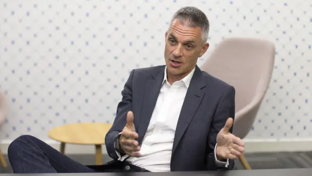 Tim Davie sitting in an armchair, gesturing with his hands