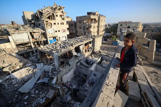صبي ينظر إلى أنقاض مبانٍ دُمرت في غارة إسرائيلية على البريج، وسط قطاع غزة، في 20 أكتوبر/تشرين الأول 2025.