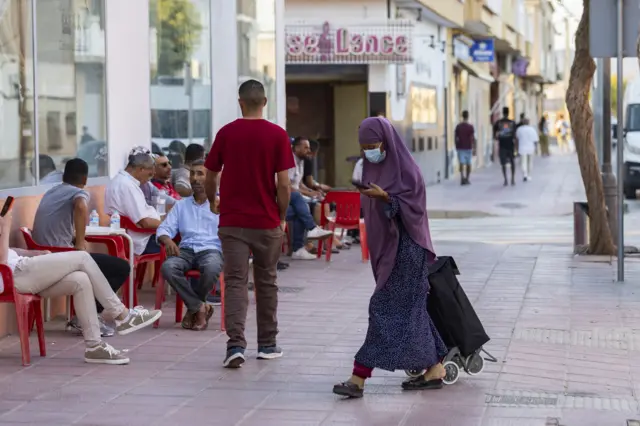 Une femme se promène dans Torre Pacheco devant une terrasse.