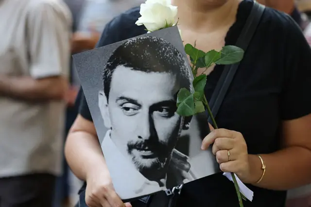 أحد المعزين يحمل وردة وصورة لزياد الرحباني، بينما تجمعت الحشود خارج مستشفى خوري في منطقة الحمرا في وسط بيروت لتوديعه قبل موكب جنازته في 28 يوليو/تموز 2025.