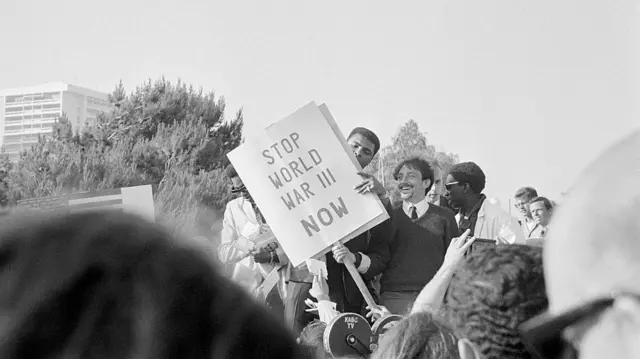 محمد علي أثناء مشاركته في احجاج مناهض لحرب فييتنام ممسكاً بلافتة تحمل شعارا باللغة الإنجليزية 