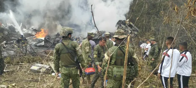 Varios soldados están parados alrededor del sitio del accidente del avión Hércules de la Fuerza Aérea Colombiana (FAC)