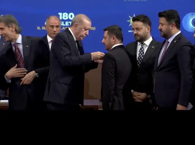 Erdoğan Arı'nın rozetini takıyor