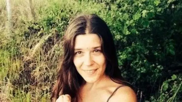 Нина Кутина улыбается на фоне зеленой растительности