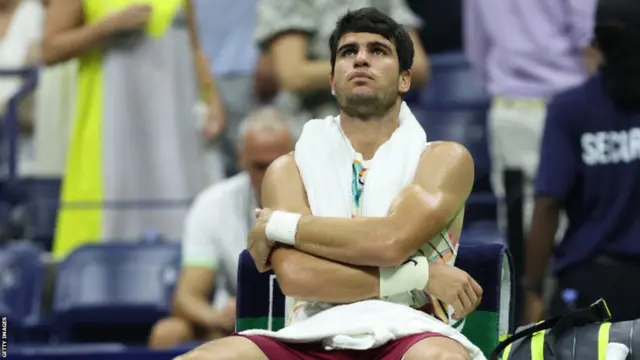 Carlos Alcaraz sits on his chair with his arms folded