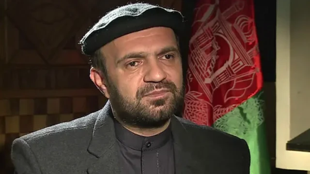 تصویر ظاهر قدیر درجلو پرچم سه رنگ افغانستان 