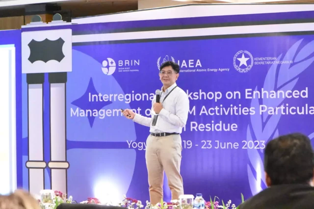 Seorang pria berkacamata sedang berbicara di depan forum.