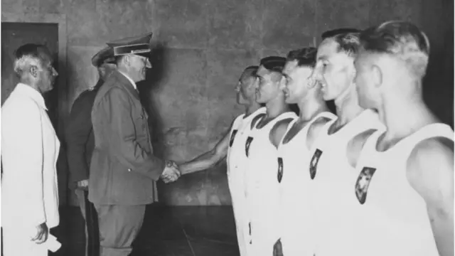 German dictator Adolf Hitler (1889 - 1945) shakes hands with British rower Jack Beresford (1899 - 1977) after he and Leslie Frank 'Dick' Southwood (1906 - 1986) won the double sculls event at the Berlin Olympics, 14th August 1936. Also present are members of the German gymnastics team. (Photo by Fox Photos/Hulton Archive/Getty Images)