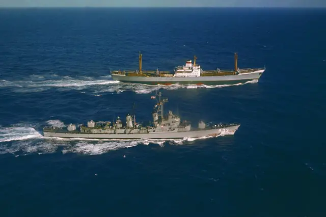 El U.S.S. Barry (a la izquierda) navega junto al carguero soviético Ansov, que salía de Cuba, para inspeccionar su carga. El Barry no envió personal a bordo. El encuentro tuvo lugar a 565 millas al norte-noreste de Puerto Rico. La cubierta del Ansov estaba cubierta con equipo militar, incluyendo ocho grandes objetos alargados que parecían ser misiles soviéticos.