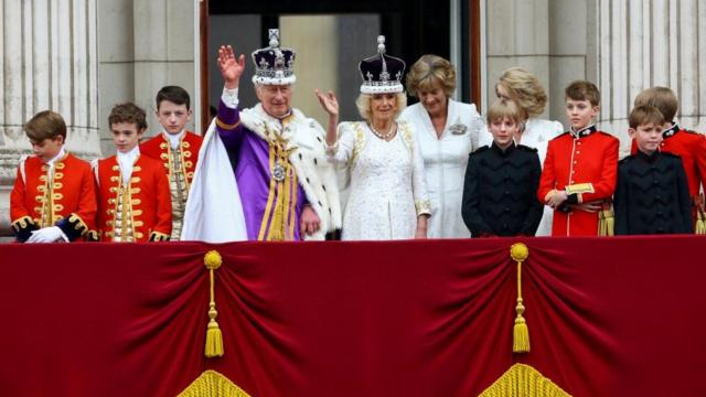 バッキンガム宮殿のバルコニーに出て、宮殿前に集まった人たちに手を振る国王夫妻