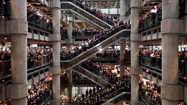 Workers stand for a poppy drop during a Remembrance Service at the Lloyd"s building in the City of London