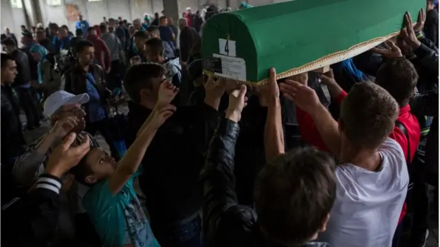 Grupa ljudi nosi tabut