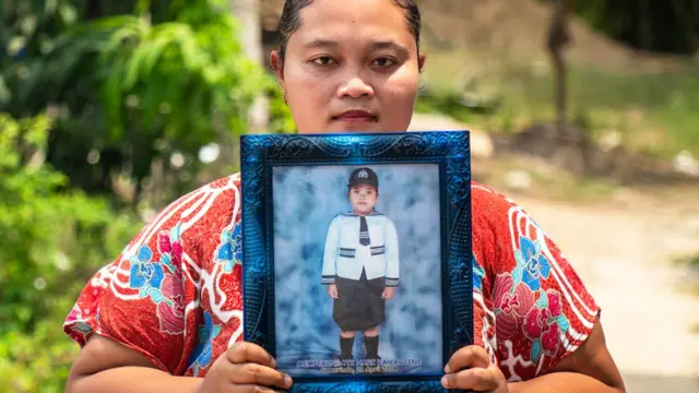 Purwanti with a photo of her daughter who drowned in an abandoned pit