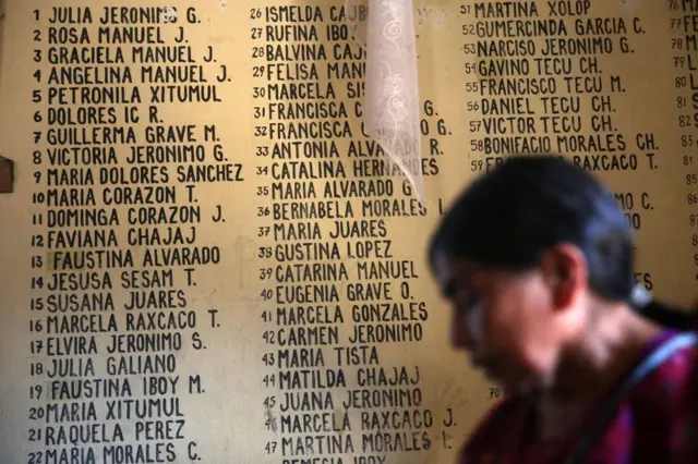 Mujer ante un cartel que recuerda a las víctimas de la masacre en Plan de Sánchez, Baja Verapaz, Guatemala.