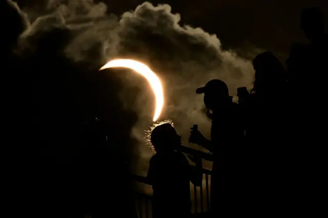 La luz del eclipse se refleja sobre el perfil de un hombre y un niño que hablan sobre el fenómeno en España.