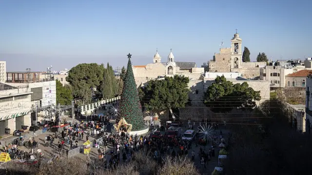 Общий вид площади перед церковью Рождества Христова с рождественской ёлкой и толпой празднующих 24 декабря 2025 года в Вифлееме, Западный берег. 