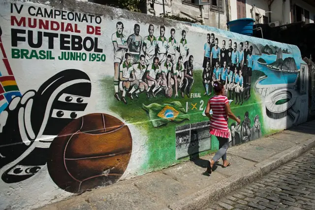 Une femme passe devant une fresque murale représentant la finale de la Coupe du monde de la FIFA 1950, Brésil-Uruguay, à Rio de Janeiro, le 8 avril 2014, au Brésil. L'Uruguay a remporté la finale 2-1.