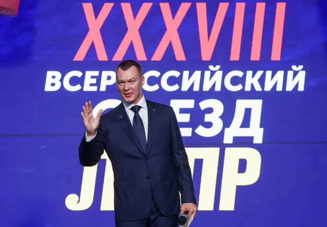 Министр спорта Дегтярев машет рукой, за его спиной баннер с надписью "XXXVIII всероссийский съезд ЛДПР"
