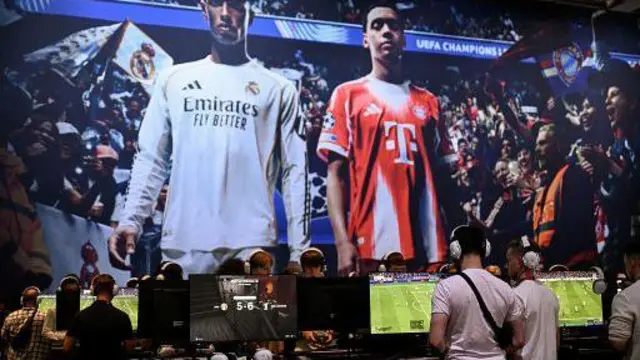 Геймери грають у відеогру "EA Sports FC 26" перед екраном із зображенням англійського півзахисника Джуда Беллінгема (ліворуч) та німецького півзахисника мюнхенської "Баварії" Джамаля Мусіали (праворуч) під час виставки відеоігор Gamescom у Виставковому центрі в Кельні, західна Німеччина.