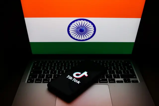 صورة لعلم الهند على حاسوب محمول وشعار تيك توك على هاتف محمول