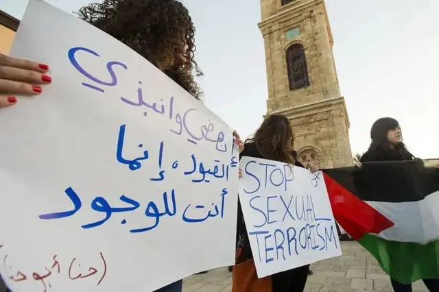 چند زن در تجمع اعتراضی با پلاکاردهایی در دست