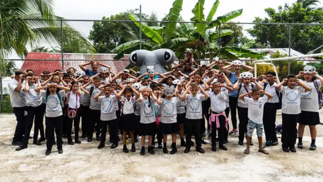 Niños con máscaras de tiburón y un tiburón inflable de juguete gigante