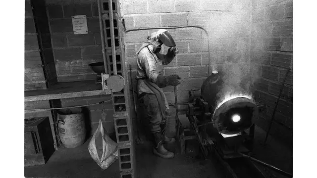 Hombre trabajando el oro en un horno.