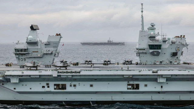 HMS Prince of Wales (foreground) with F-35B Lightning jets on deck, and USS Harry S. Truman (Background)