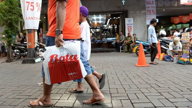 Foto ilustrasi: Seorang pembeli membawa kantong plastik bermerek dari toko Bata, sambil berjalan.