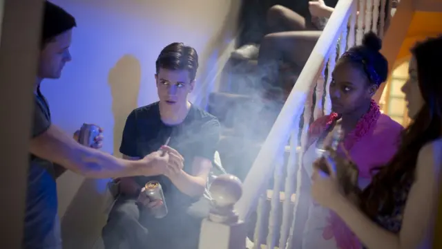 Adolescentes bebiendo y fumanod en una fiesta en una casa