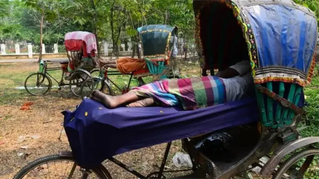 প্রচণ্ড গরমে কাজ বন্ধ রেখে বিশ্রাম নিচ্ছেন একজন রিক্সাচালক