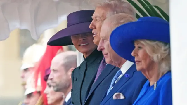 Подружжя Трампів, король, королева, Кетрін та Вільям стоять в ряд і дивляться вперед. Меланія повернула голову до камери, її очі закриває капелюх