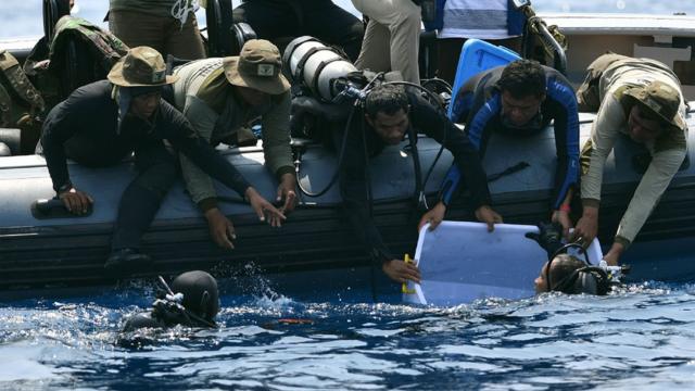 Indonesian Navy diver (bottom L) holding a recovered "black box" under water before putting it into a plastic container (R)