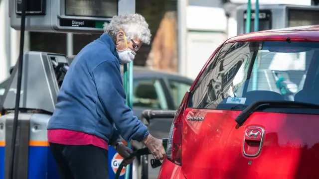 লন্ডনে পেট্রল পাম্পে গাড়িতে তেল ভরছেন এক নারী (২১শে এপ্রিল ২০২০)