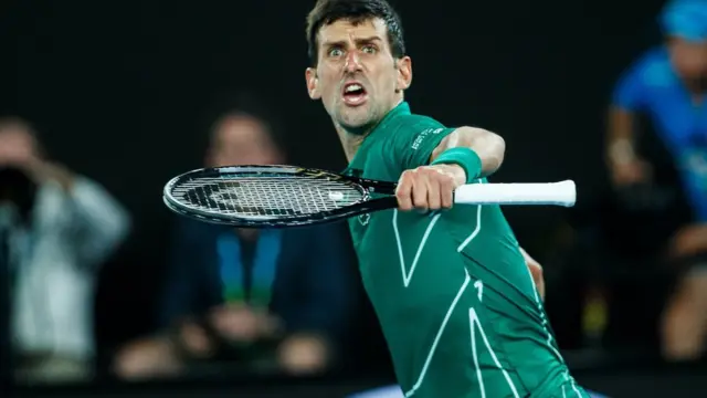 Novak Djokovic marque un point lors de son match de demi-finale contre le Suisse Roger Federer, lors de la onzième journée de l'Open d'Australie 2020, le 30 janvier 2020 à Melbourne, en Australie.