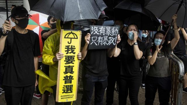 香港市民拿着标语，到法院大楼外声援被控“暴动”的人。