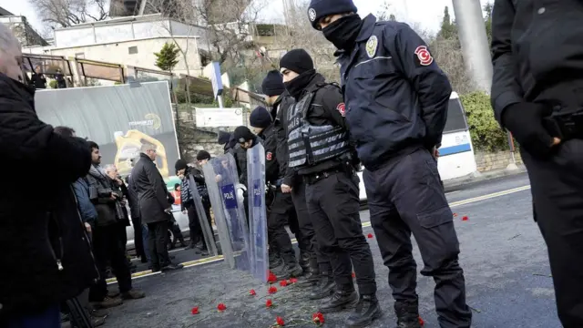 Flowers are placed next to Turkish police officers as they stand guard near the Reina nightclub, which was attacked by a gunman, in Istanbul, Turkey, on 1 January 2017