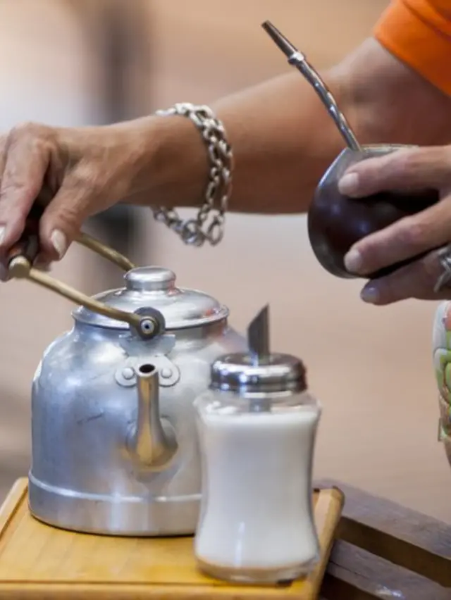 Mujer cebando mate con pava y azúcar.