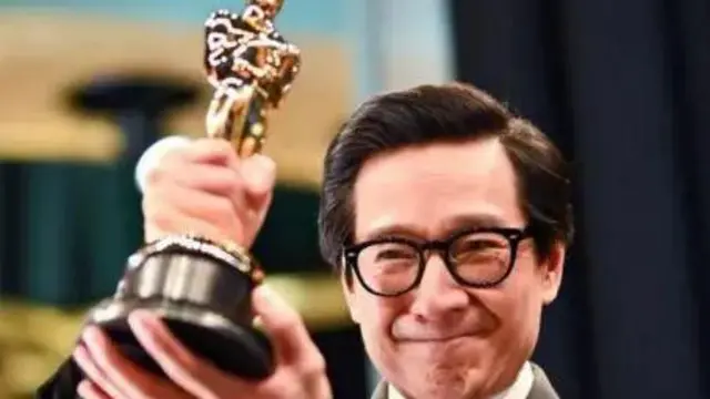 که هوی کوان تندیس اسکار را در دست گرفته و خوشحالی خود را ابراز میکند