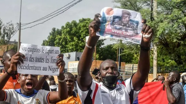 Protesters walk down the street holding banners calling for western troops to leave Niger