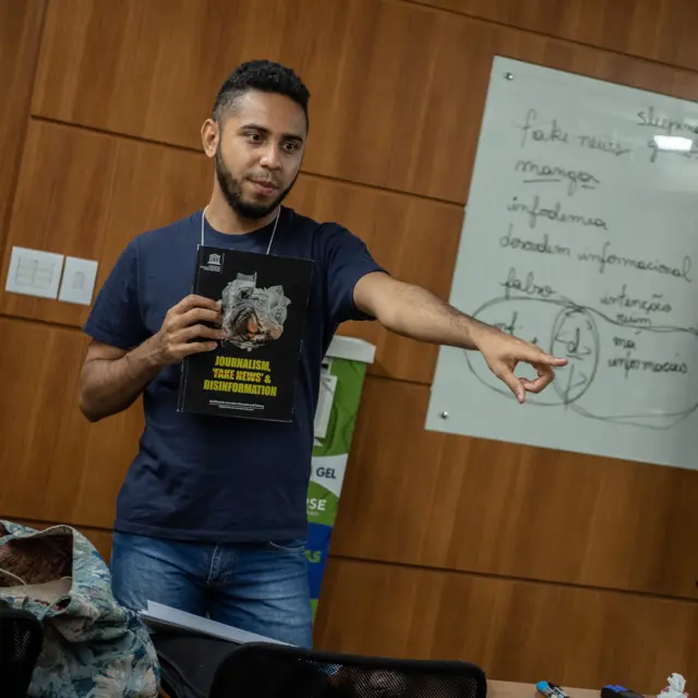 Gustavo Souza, pesquisador da organização Desvelar, em palestra, usando camiseta e calça jeans