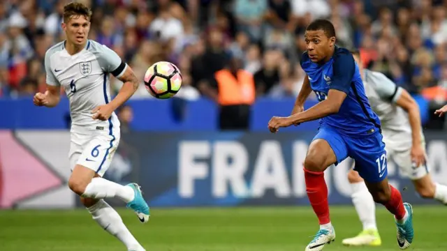 Kylian Mbappe melewati John Stones dari timnas Inggris dalam laga persahabatan pada 2017.