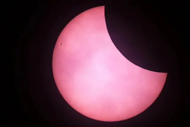 A Lua bloqueia parcialmente um Sol vermelho nesta foto do Observatório de Greenwich, em Londres