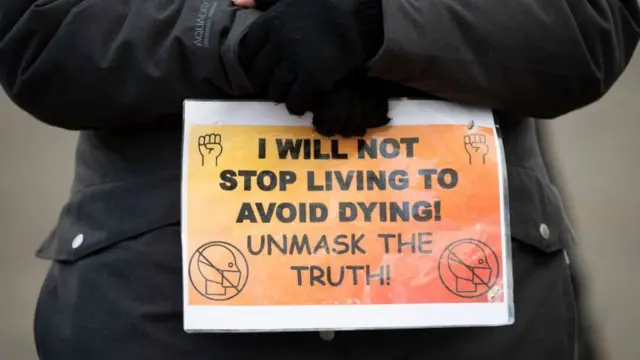 ব্রিস্টলে ১২ ডিসেম্বর ভ্যাকসিন বিরোধী সমাবেশে প্লাকার্ড হাতে একজন