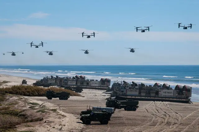 Военная техника на пляже, сверху летают вертолеты