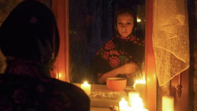 Uma garota em frente ao espelho com uma vela na mão